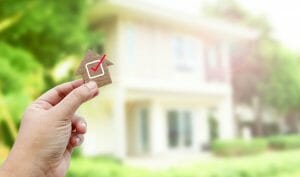 Person holding a tiny home with a checkmark in front of a house