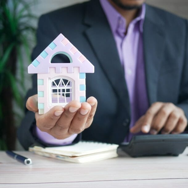 Business Man Holding Tiny House